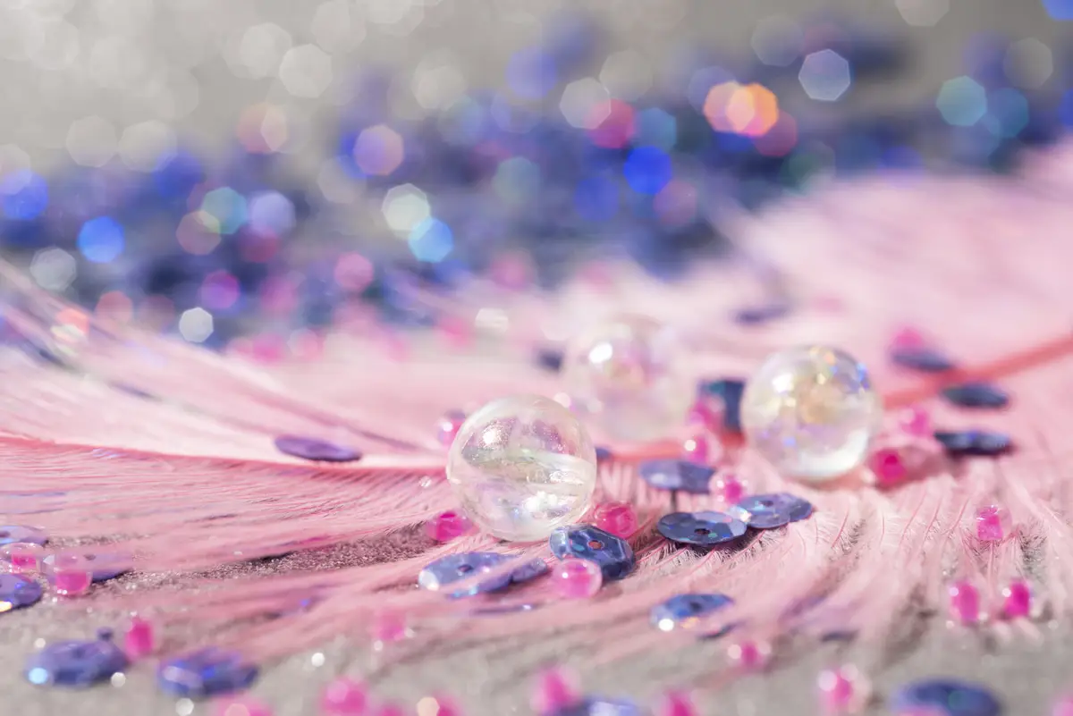 Close up on feather with confetti, sparks and glitter