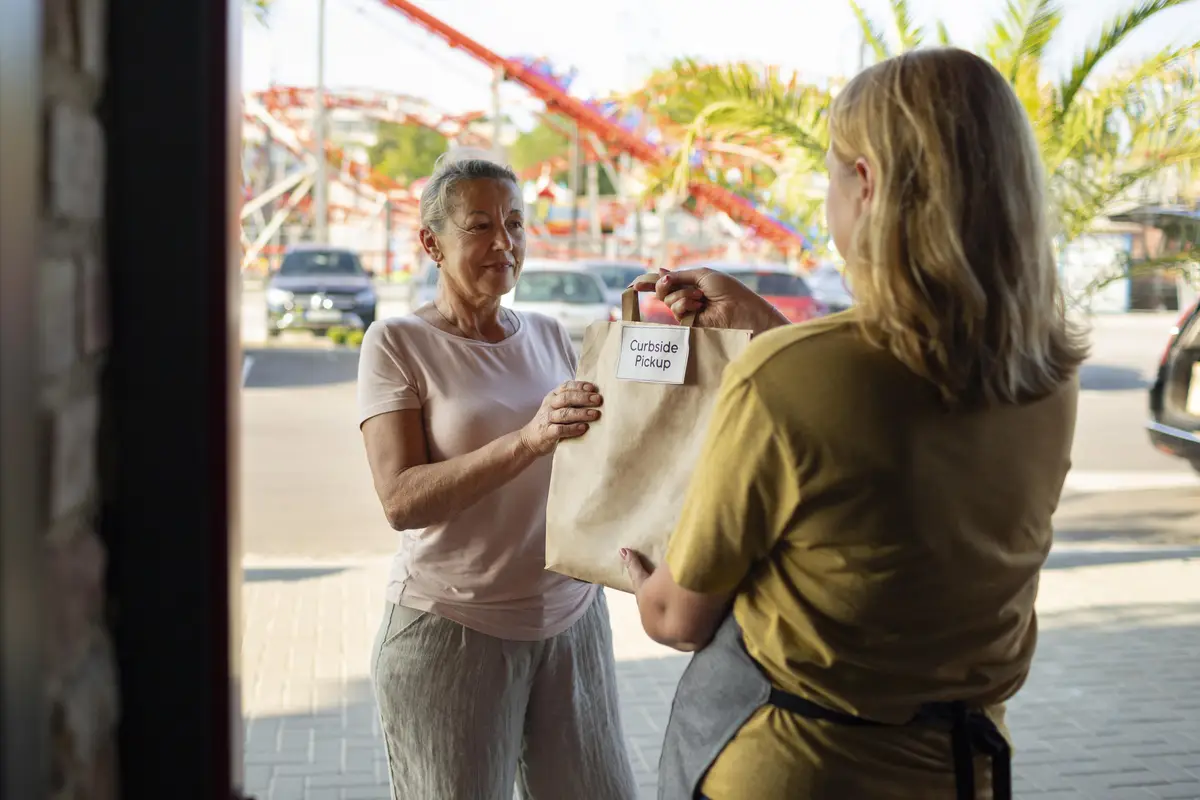 Woman giving an order to a customer at a curbside pickup outside