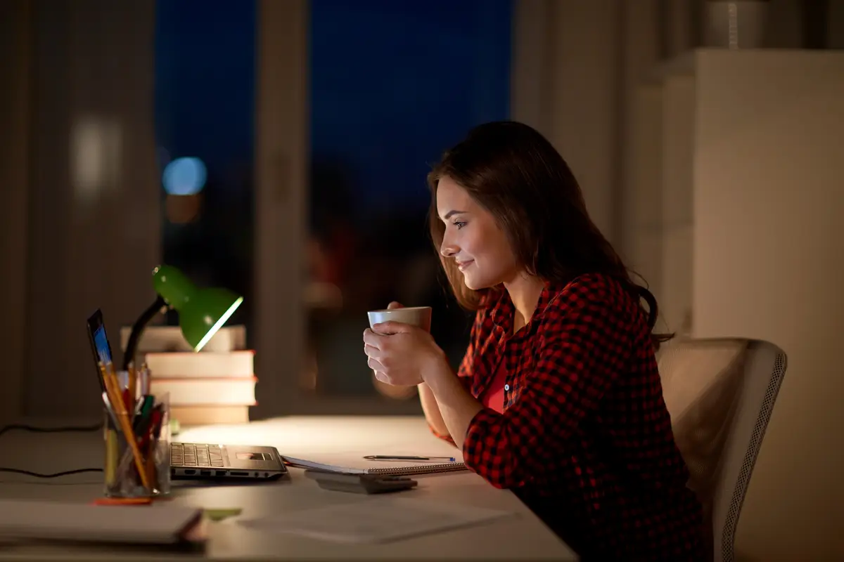 education, technology, freelance, overwork and people concept - woman or student girl with laptop computer drinking coffee at night home