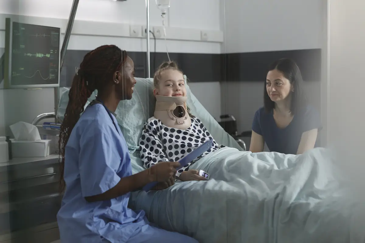 Unwell suffering kid recovering in pediatric hospital ward while resting in patient bed. Nurse examining injured girl with fractured neck wearing cervical collar because of car accident.