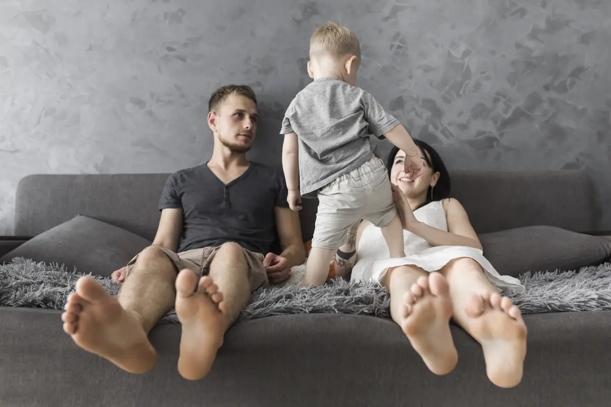 Little boy playing with his parents sitting on sofa at home