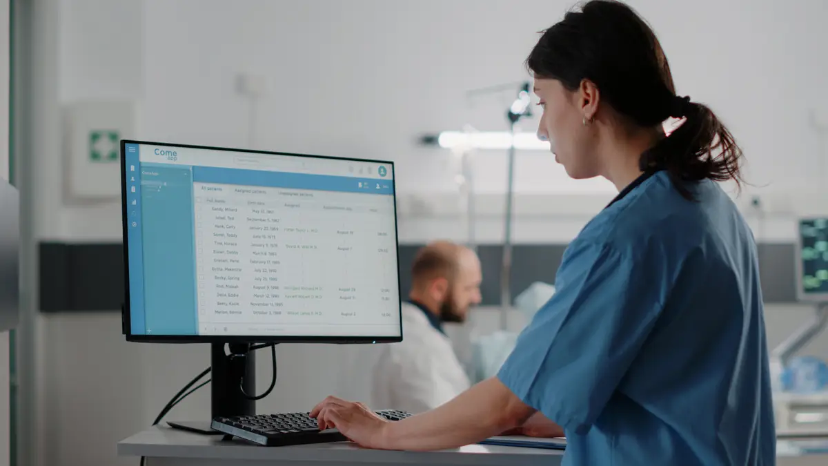 Close up of woman nurse working on computer in hospital ward. Medical assistant typing on keyboard while looking at monitor with healthcare files for treatment and recovery. Health specialist