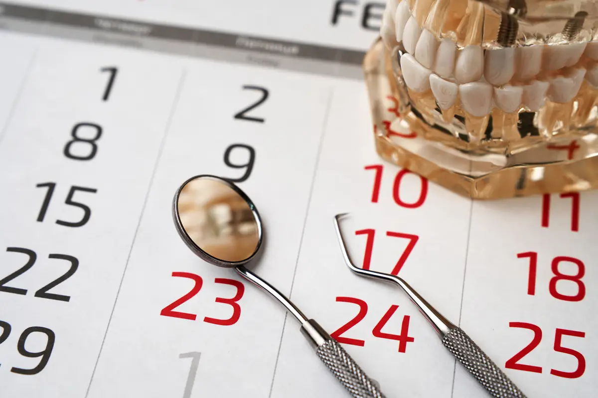 Dentist appointment calendar page and dentures model with mirror dental closeup