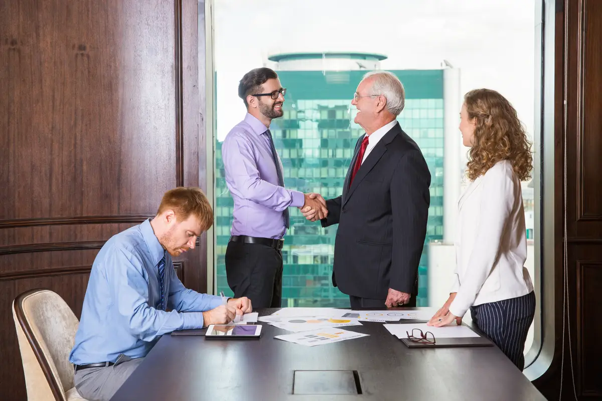 Businessmen shaking hands while another is writing