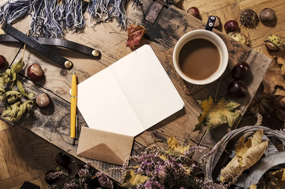 High angle view of coffee with blank book and maples leaves on wooden box
