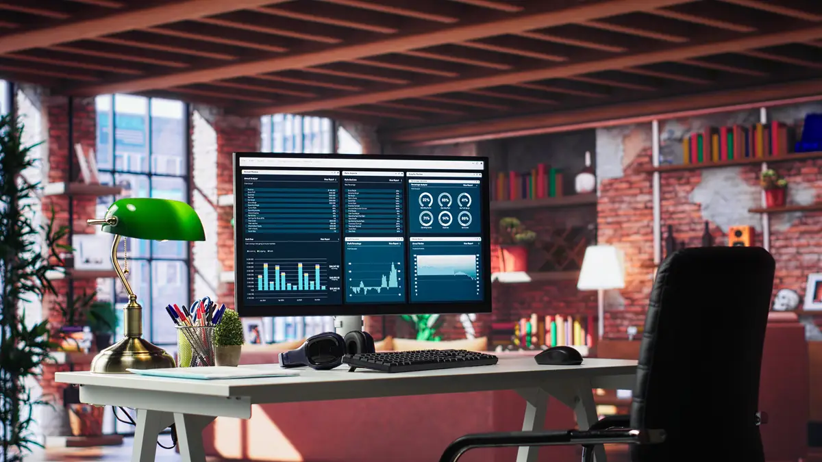 Modern home office with desktop PC monitor displaying business analytics