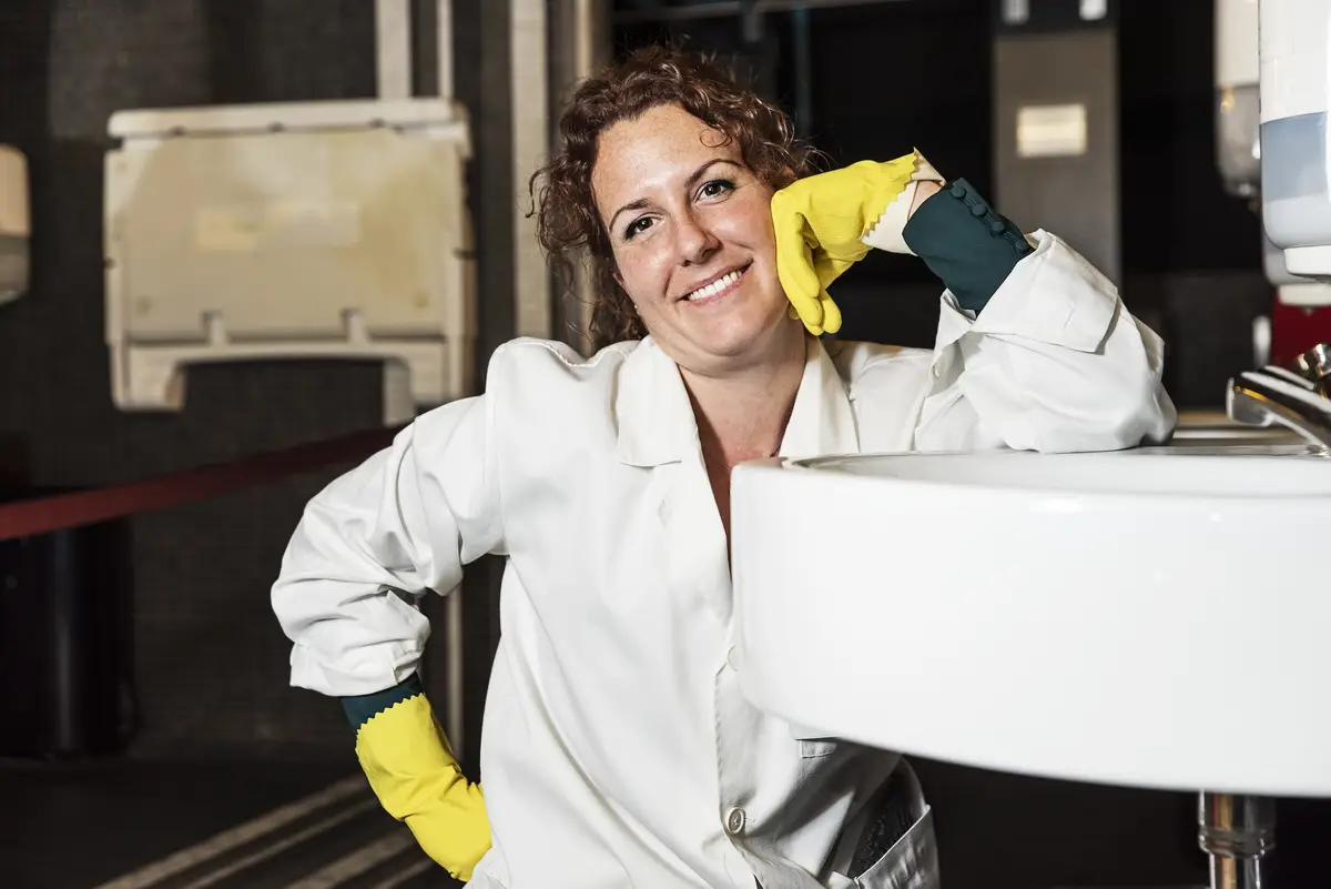 Portrait of smiling woman crouching at sink in bathroom