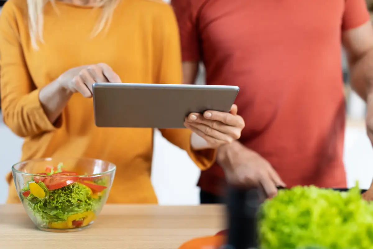 Cropped of man and woman using digital pad while cooking