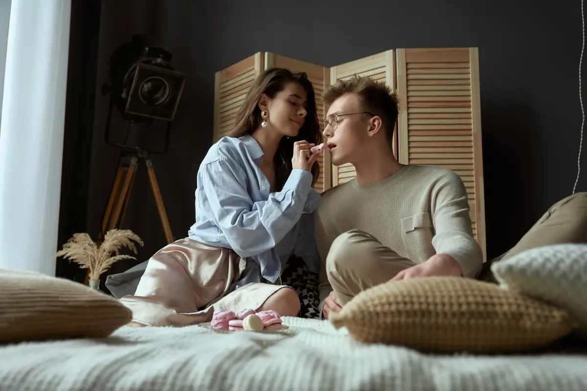 Girl feeding boyfriend on bed