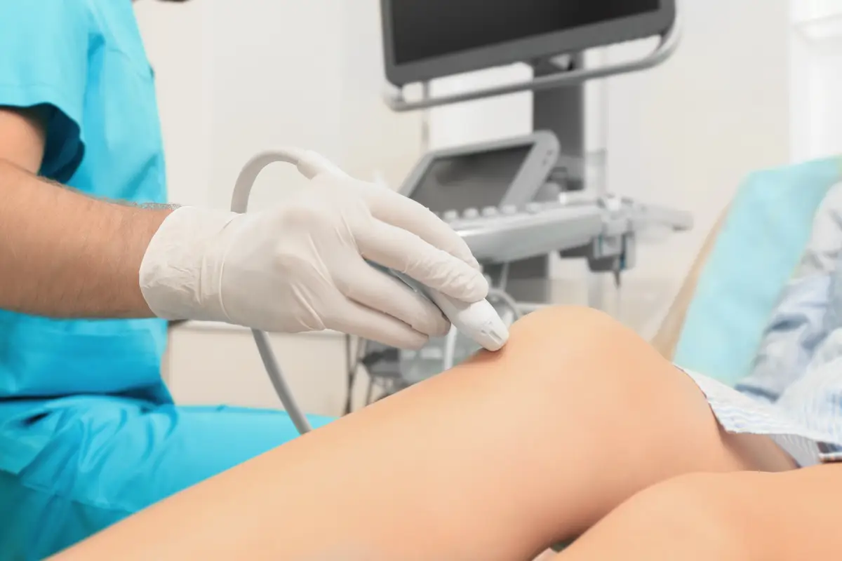 Doctor conducting ultrasound examination of patient's knee in clinic