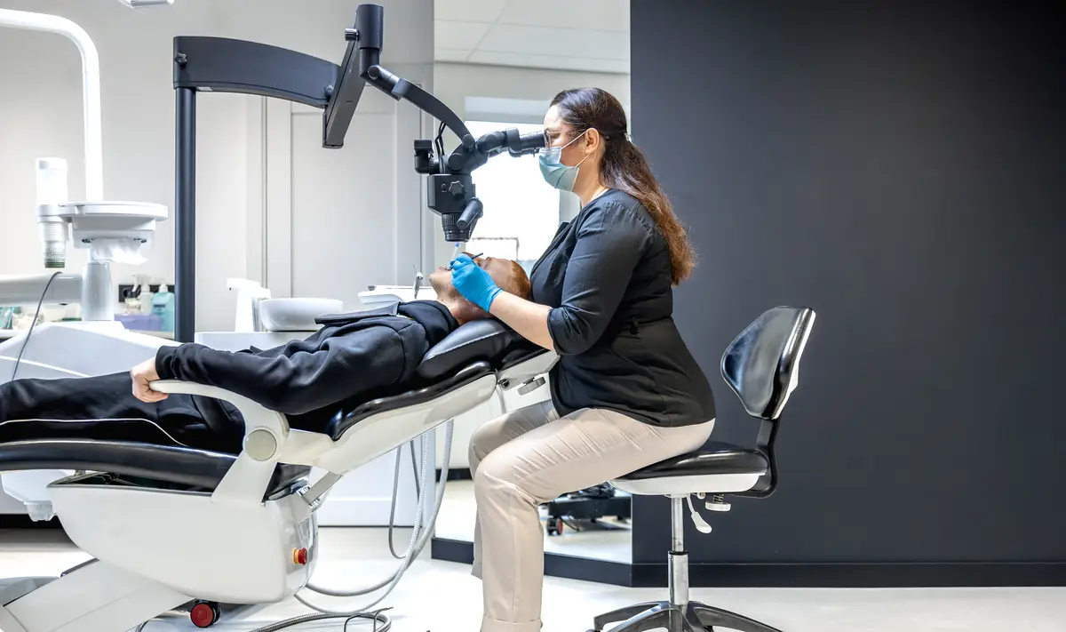 Young female dentist treating patients teeth with dental microscope Dentistry concept