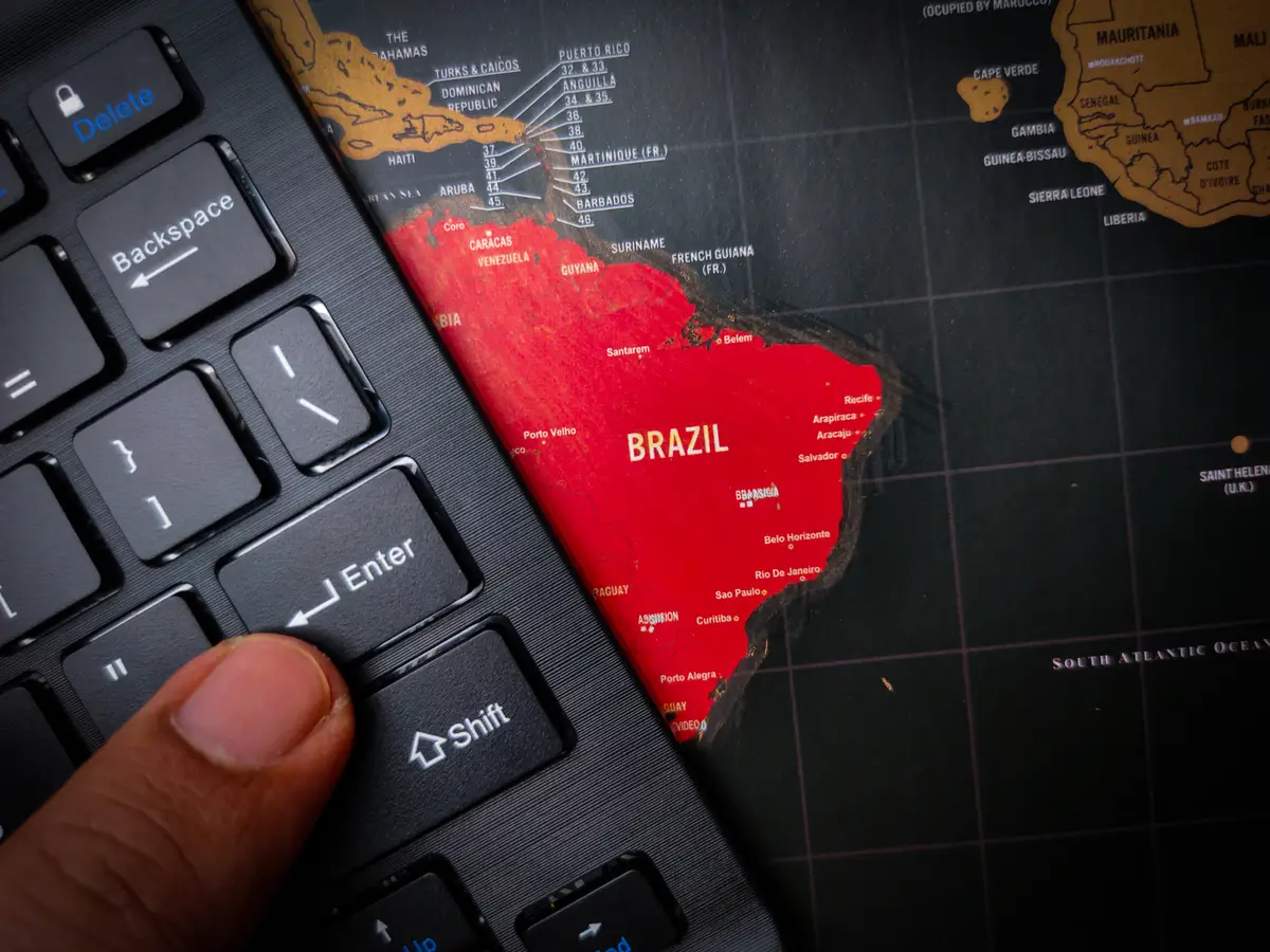 The finger is pressing enter on the black keyboard that is above the map of BRAZIL Business and political concepts