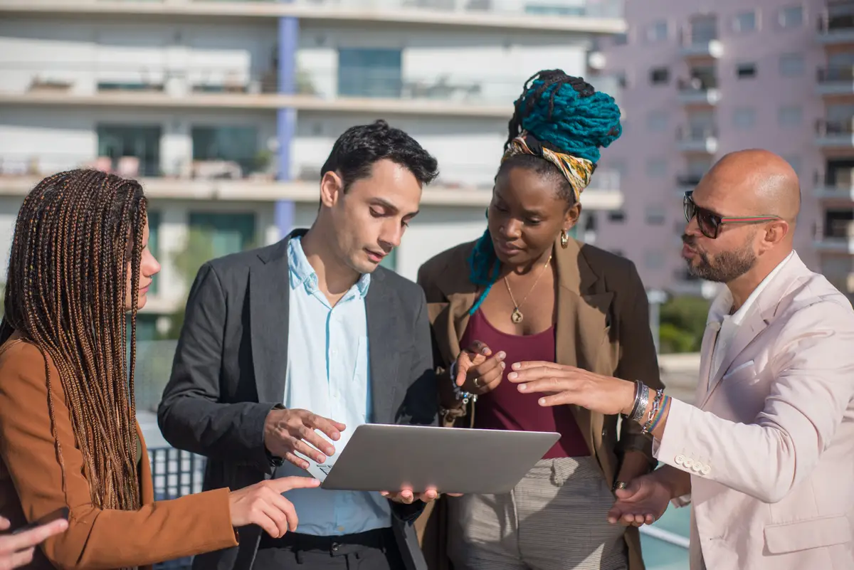 Successful business people discussing matters on terrace roof. Men and women of different nationalities on terrace roof, using laptop. Work, modern technology, team concept