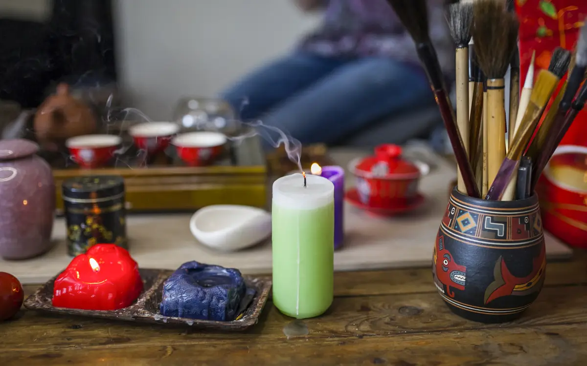 Extinguished candle with smoke in front of tea set on wooden table