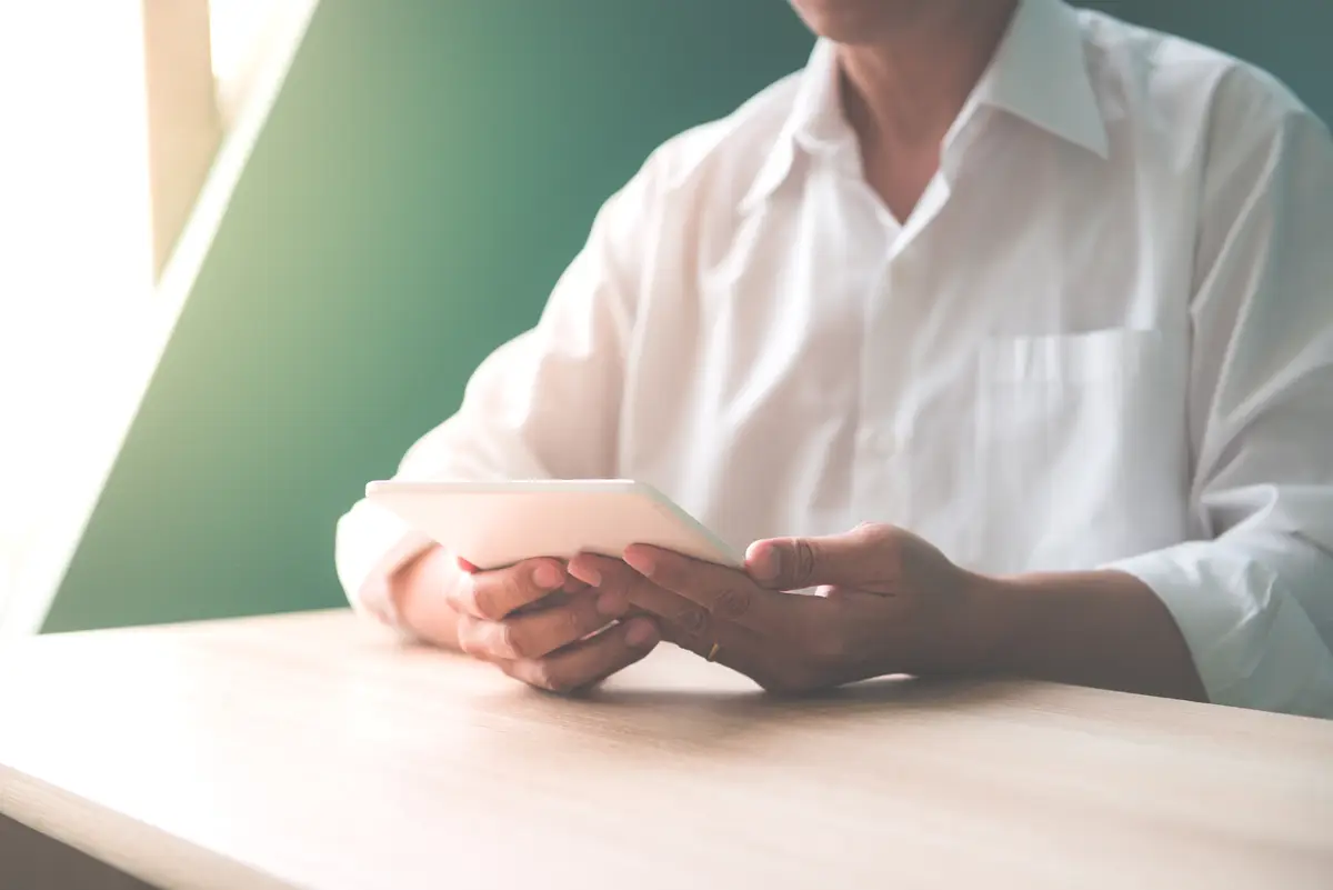 Close-up of happy smiling businessman or employer working on digital tablet and talking on his smartphone in modern office interior, flare light, Vintage effect style pictures.