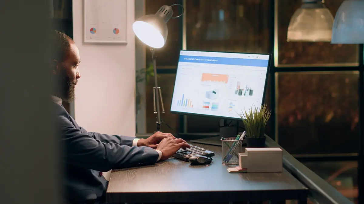 Tired bookkeeper imputing datasets online on computer, trying to keep up with project tasks before deadline. Stressed employee working overnight in office during nightshift