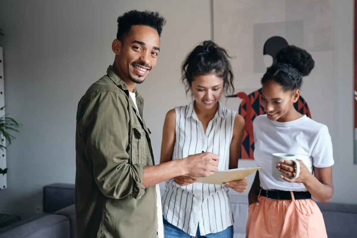 Young African American man happily looking in camera during work with colleagues in modern co-working space