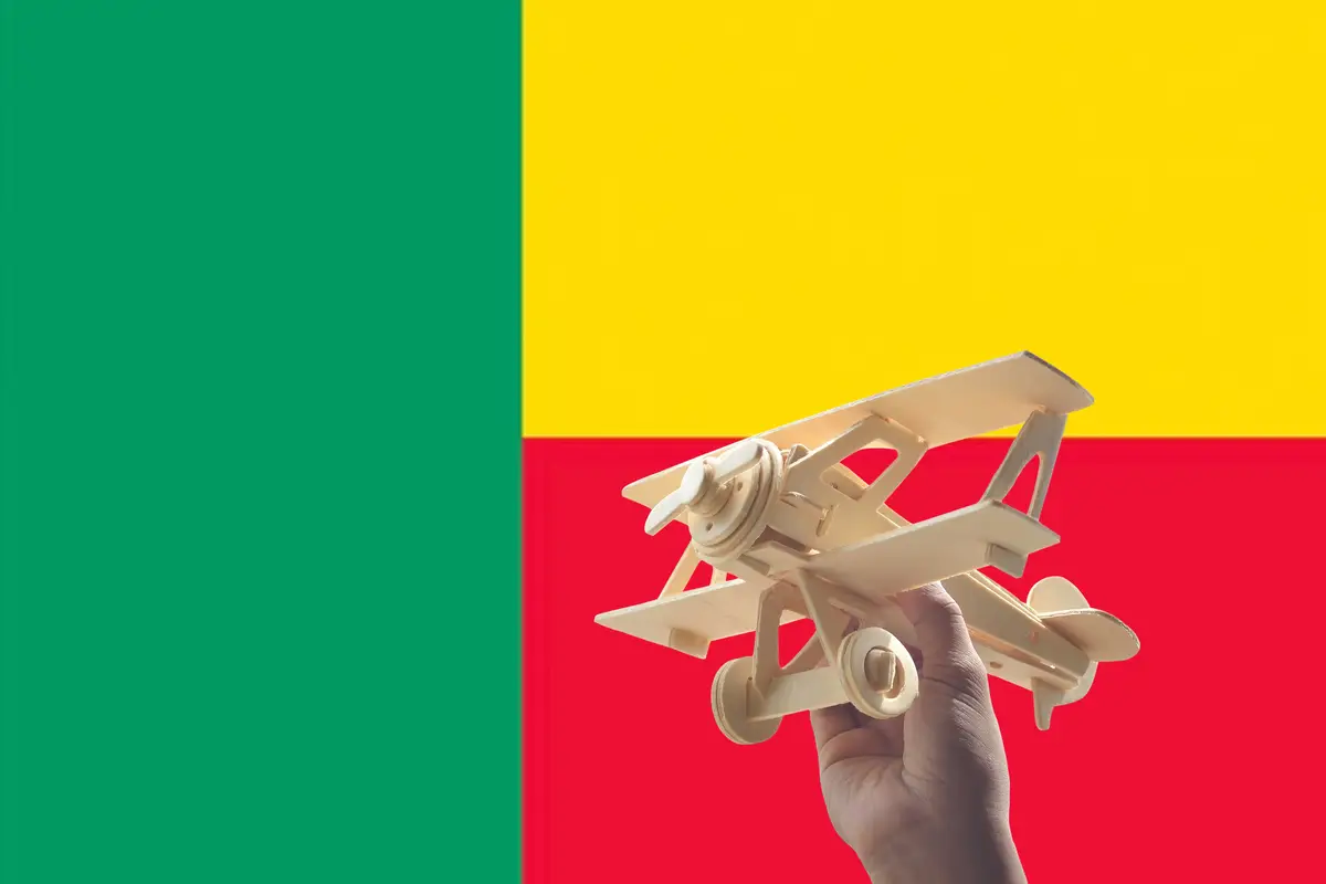 Close-up of human hand holding model airplane against flag