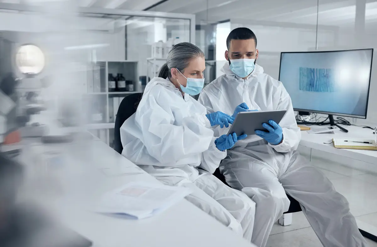 Research covid and tablet with doctors reading information for work discussion Medical team and PPE for safety health and wellness while doing research on coronavirus together in lab at hospital