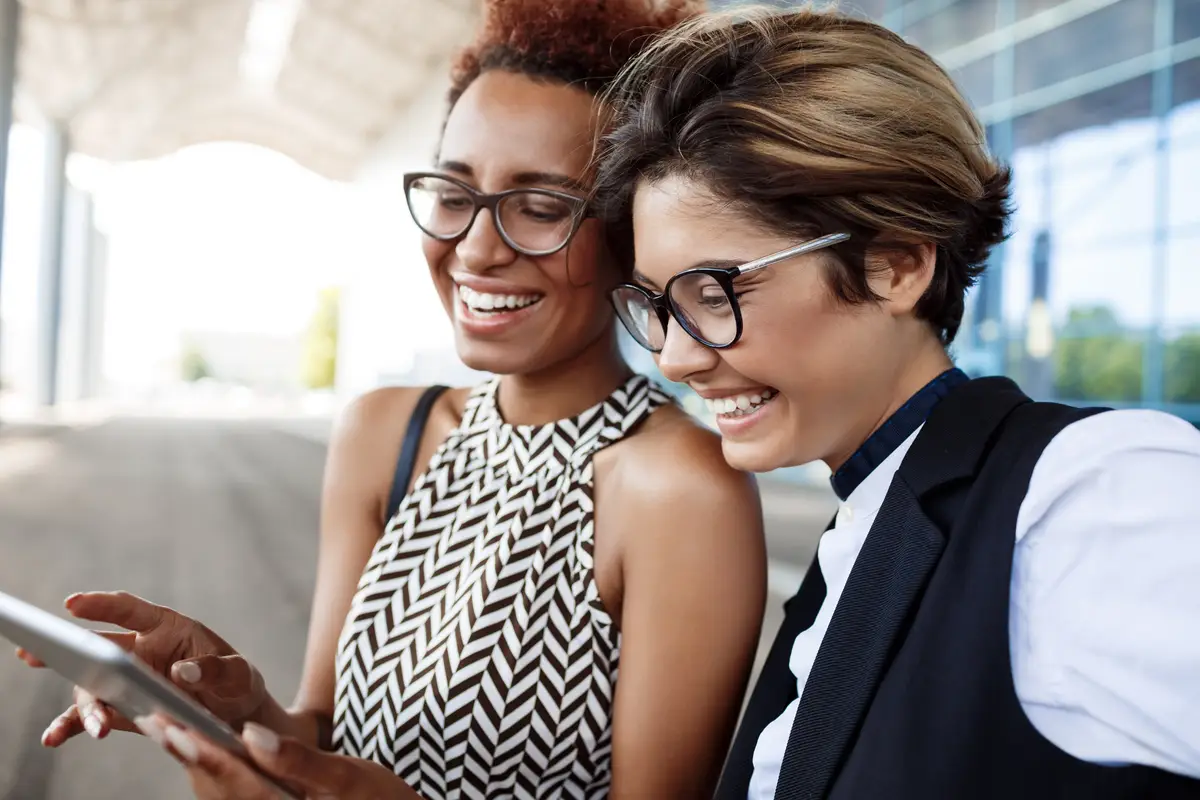 Two young successful businesswomen looking at tablet over business centre.
