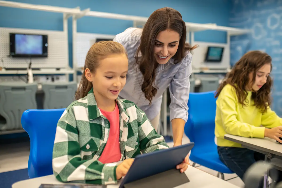 Woman looking into tablet of happy girl