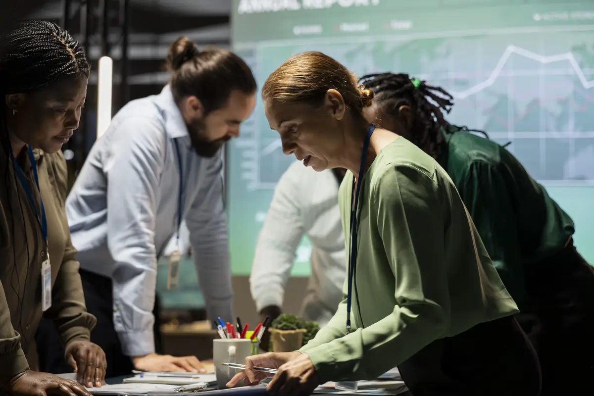 Diverse group of staff collaborating on a company briefing after hours leveraging projections and