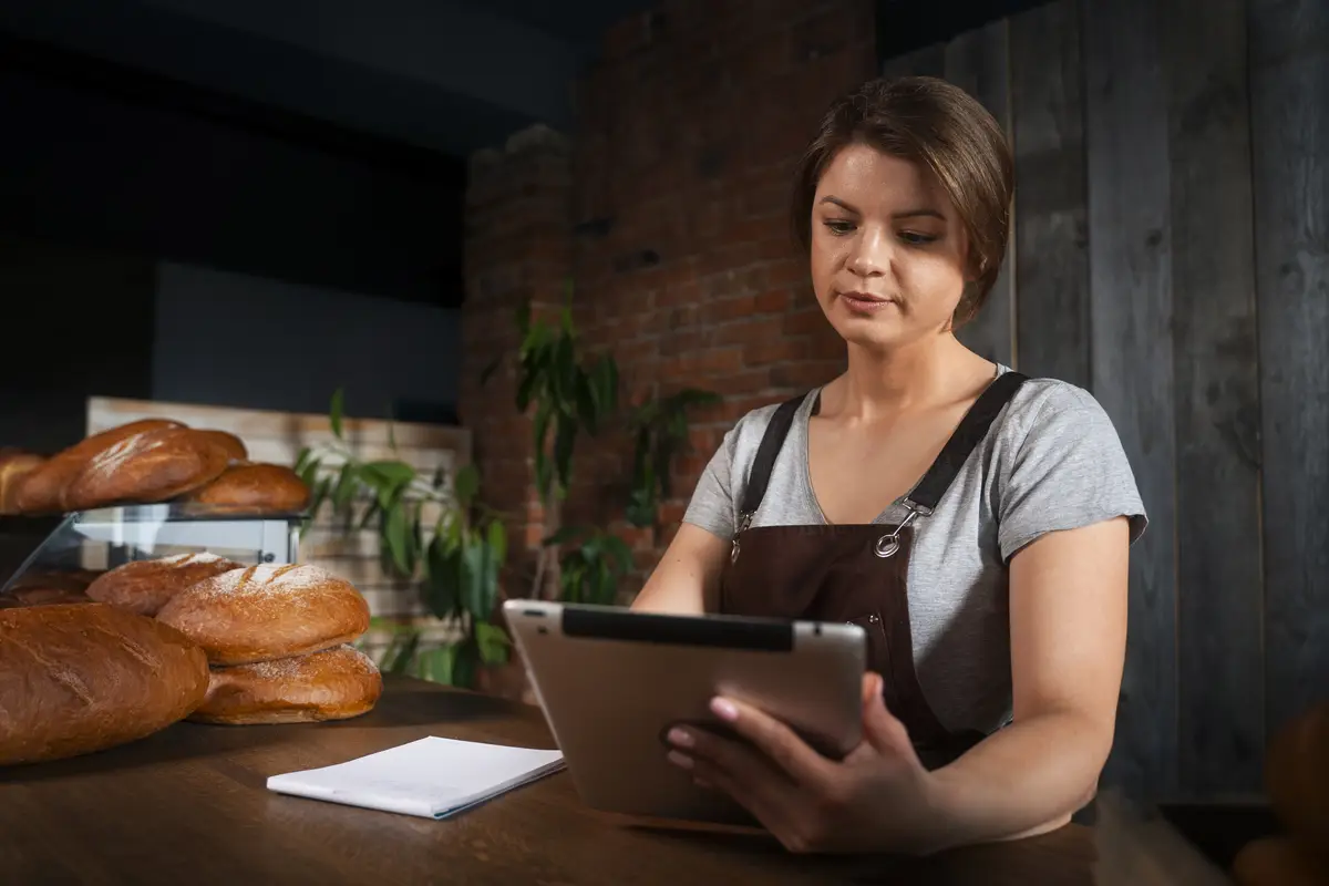 Female baker in the shop with tablet taking online orders