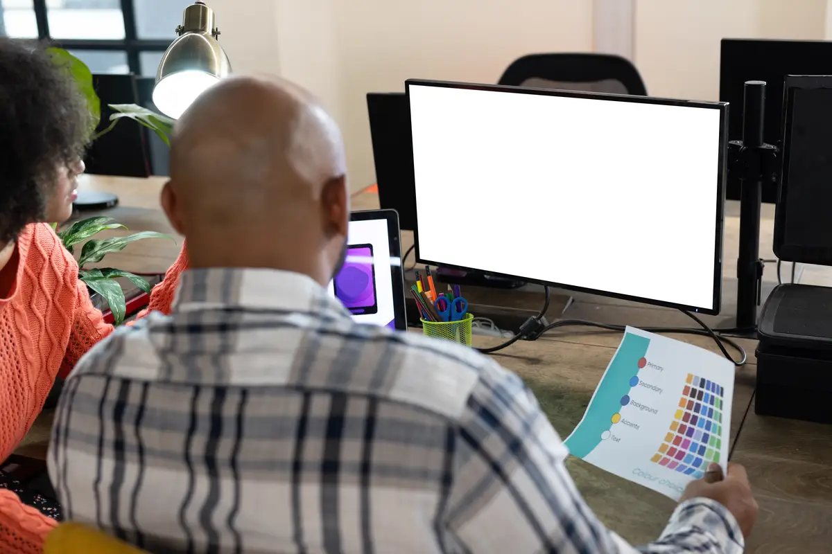 Rear view of diverse male and female designers using computer with copy space in office. Creative business, design, technology, teamwork and casual office.