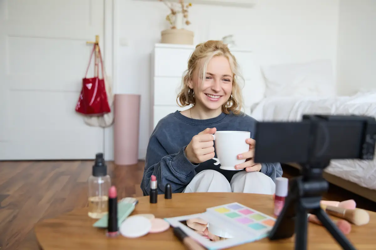 Portrait of cute smiling woman blond girl drinks tea and records a casual lifestyle video blog
