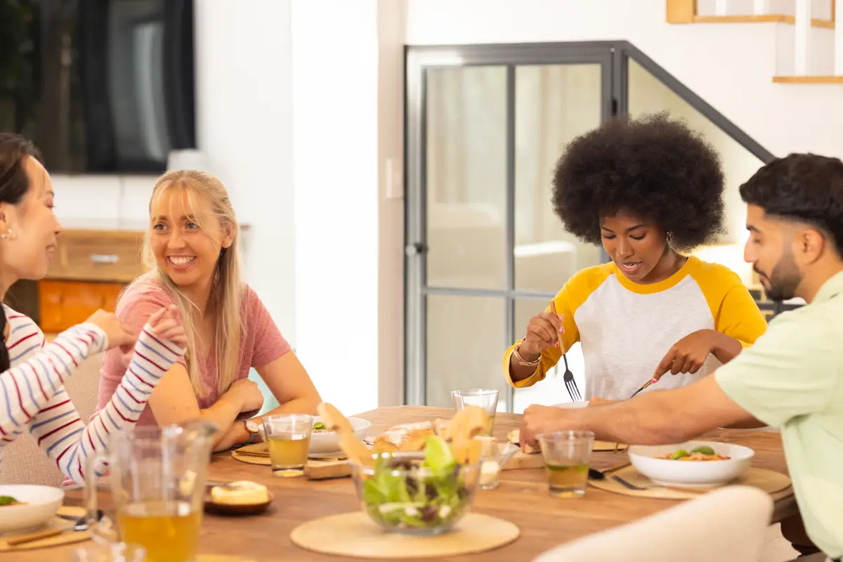 Eating lunch together group of young diverse friends enjoying meal at home