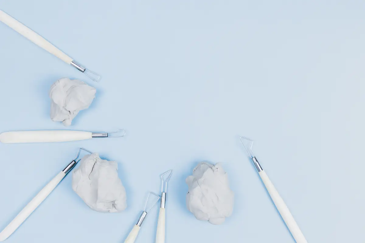 Knead clay dough with sculpting tools against blue background