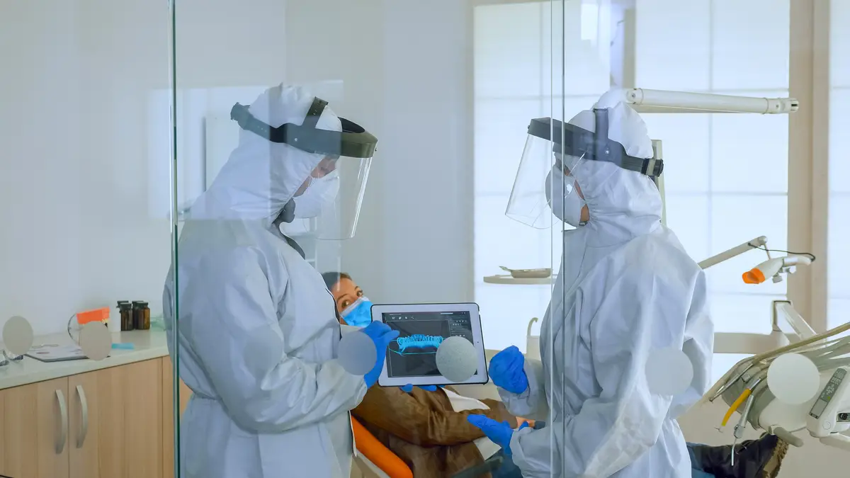 Emergência médica: diagnóstico e tratamento da mucormicose 3 Dentist doctors in overall using tablet explaining dental x ray in stomatologic office during coronavirus. Man wearing face shield and mask showing to nusrse radiography using digital device