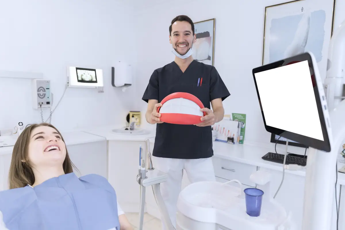 Happy male dentist holding big teeth model in the clinic