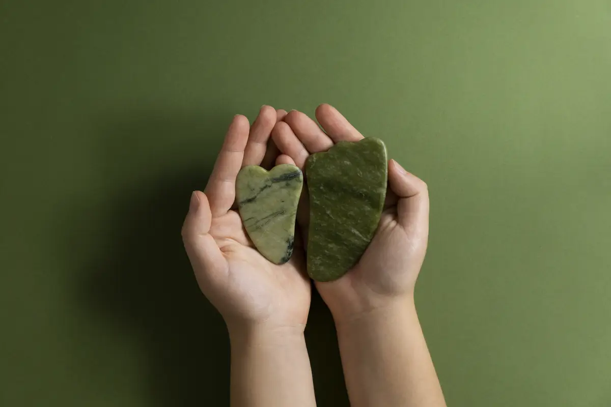 Top view hands holding green gua sha