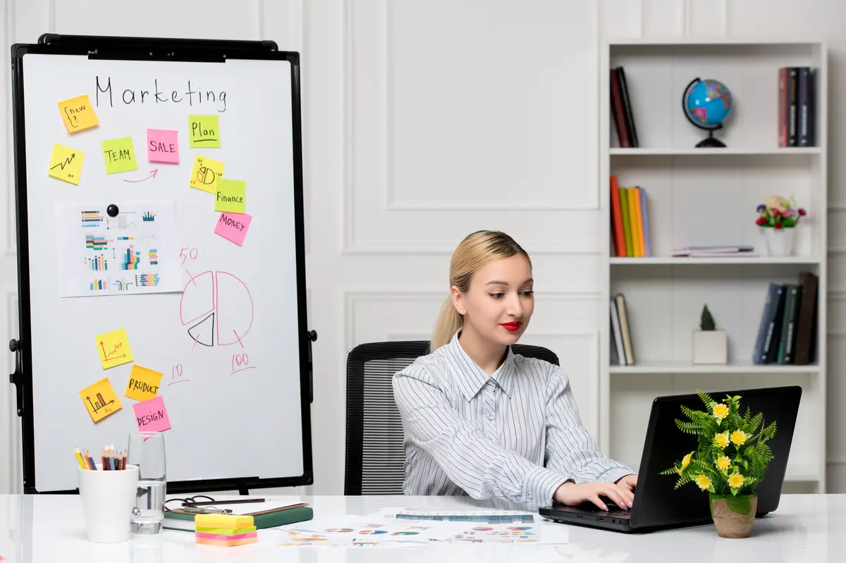 Marketing smart cute business lady in striped shirt in office typing on computer and smiling