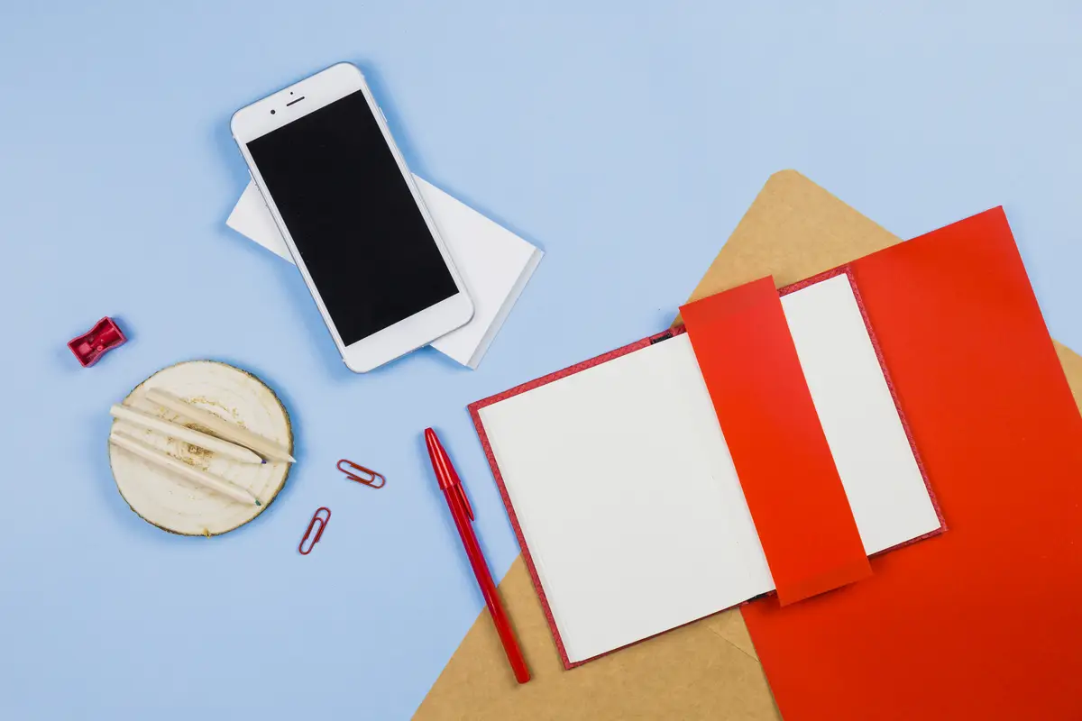 Smartphone with notebook and pencils