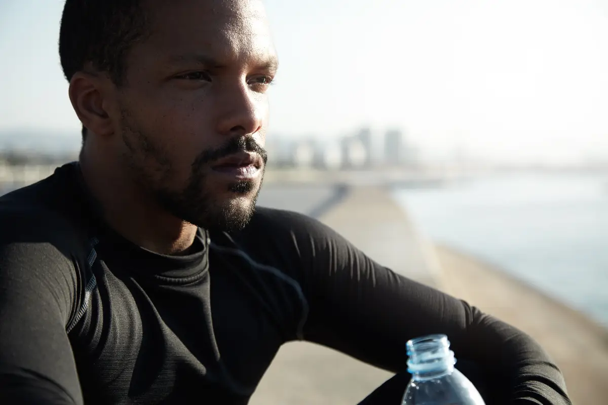 Young fit man at the beach drinking water