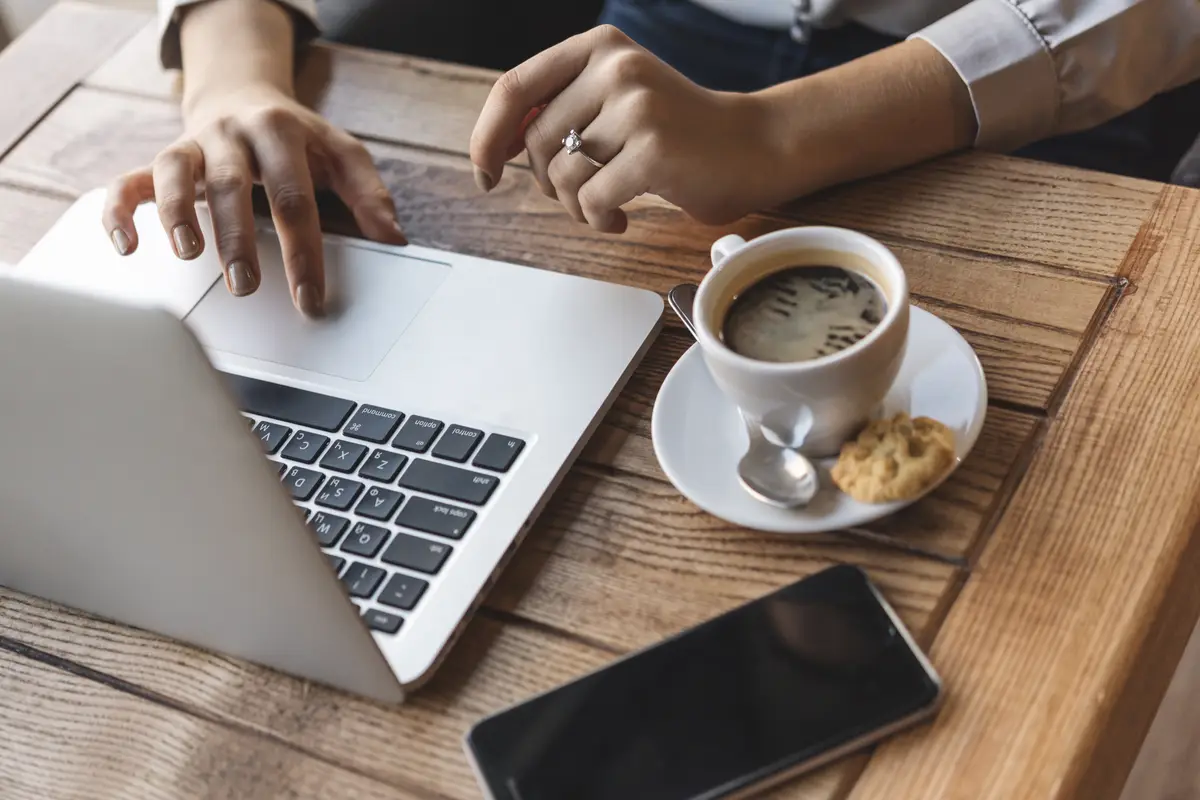 Close up of woman typing on laptop in coffee shop