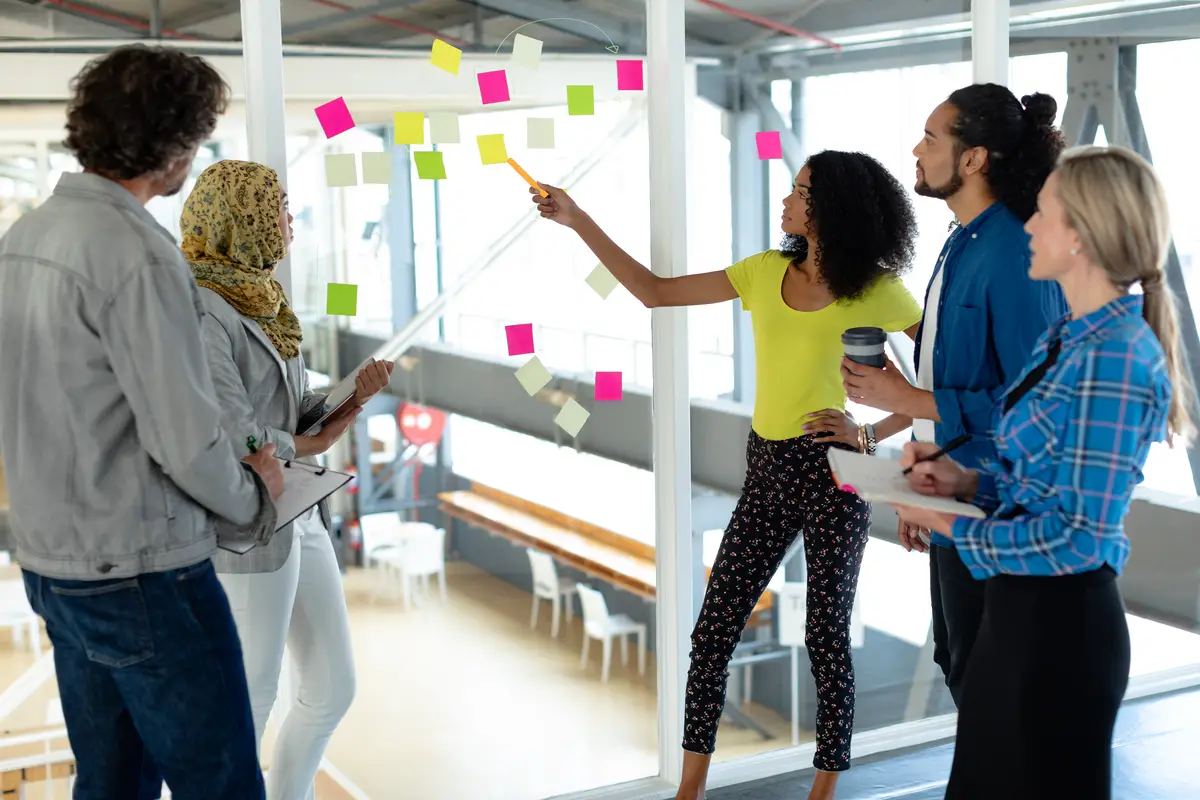Business people discussing over sticky notes on glass wall in a modern office