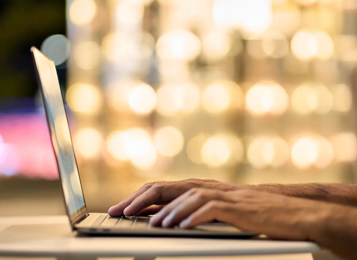 Business man hands typing on laptop keyboard on night lights background