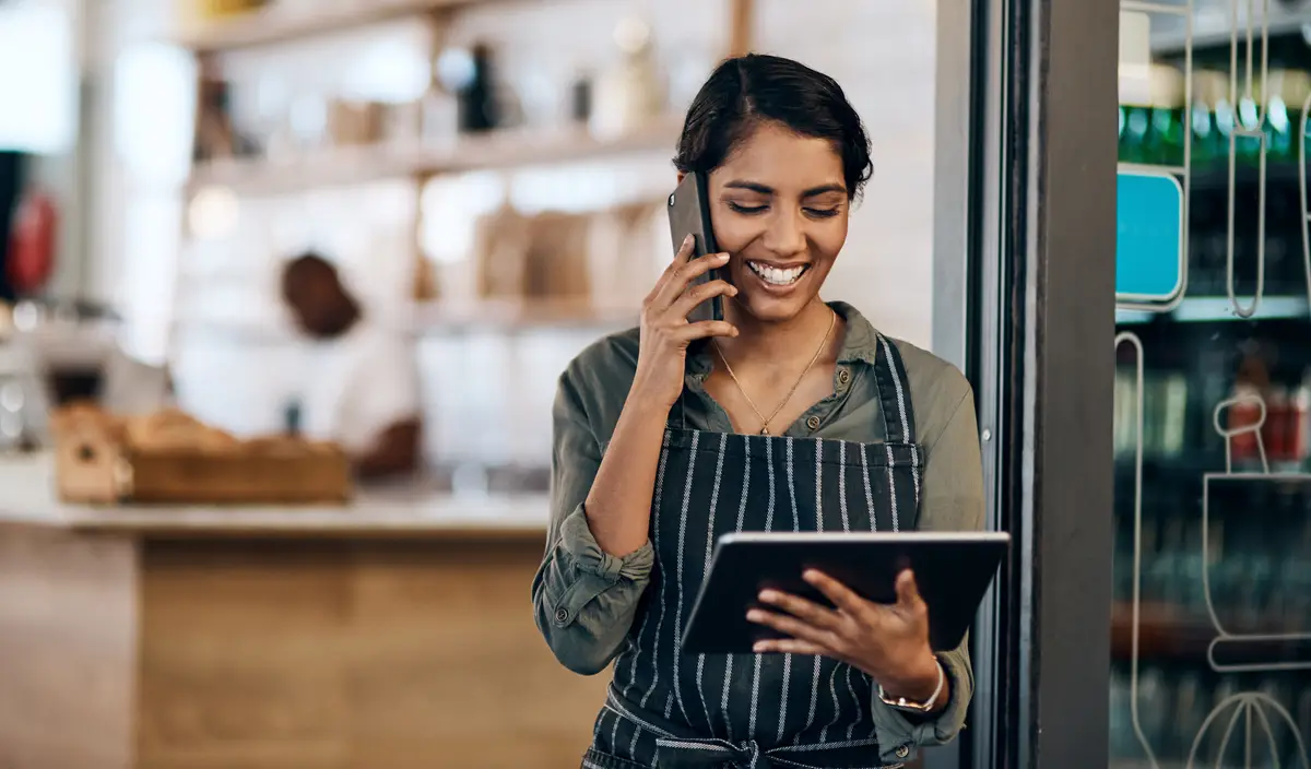 The wireless barista Shot of a young woman using a digital tablet and smartphone while working in cafe