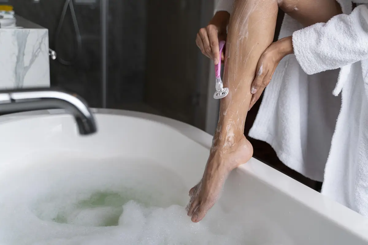 Woman shaving her lag before taking a bath