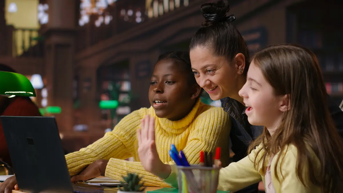 Multiethnic scholars in the library engaged in remote learning with their mentor