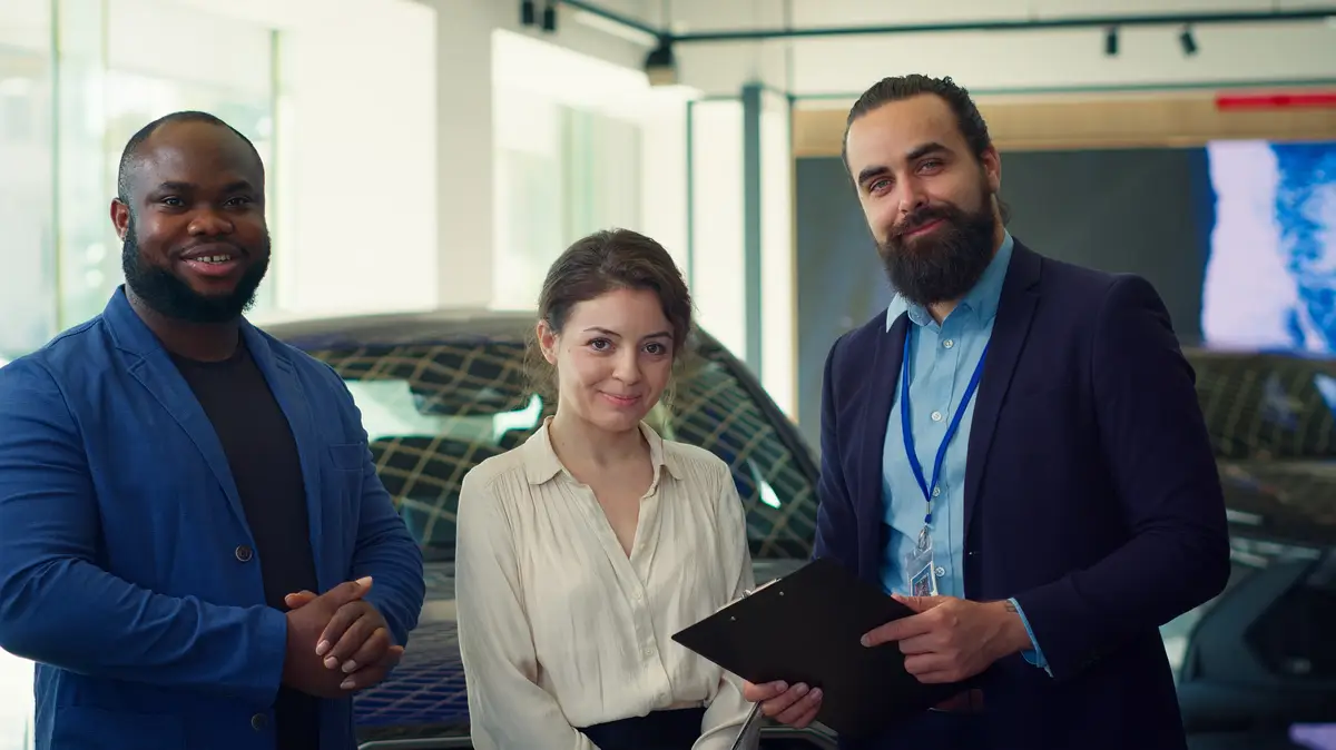 Portrait of happy salesman talking with clients showcasing dealership vehicle