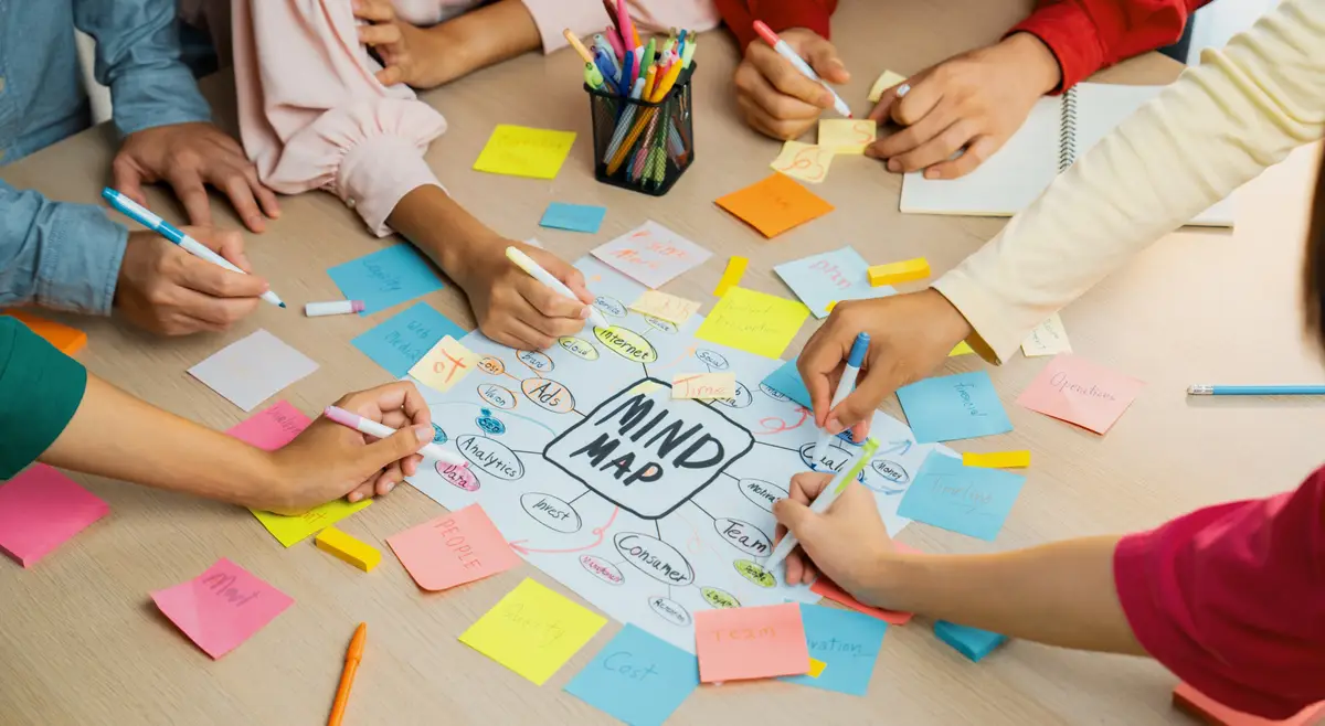 Professional startup group share creative marketing idea by using mind map Young skilled business people brainstorm business plan while writing sticky notes Focus on hand Closeup Variegated