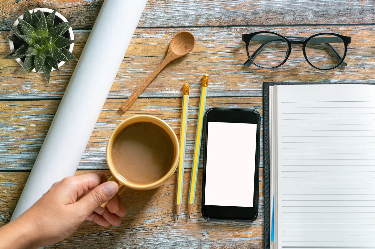 Woman in yellow sweater is reading book while drinking coffee mockup template
