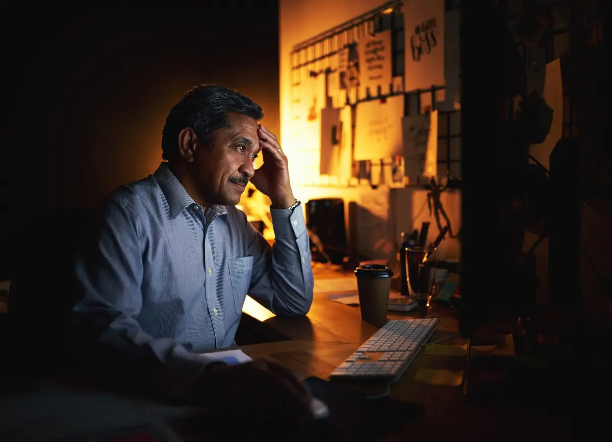Mature businessman stress and night with headache on computer for deadline overworked or burnout at office Man or employee working late with migraine strain or pressure for project at workplace