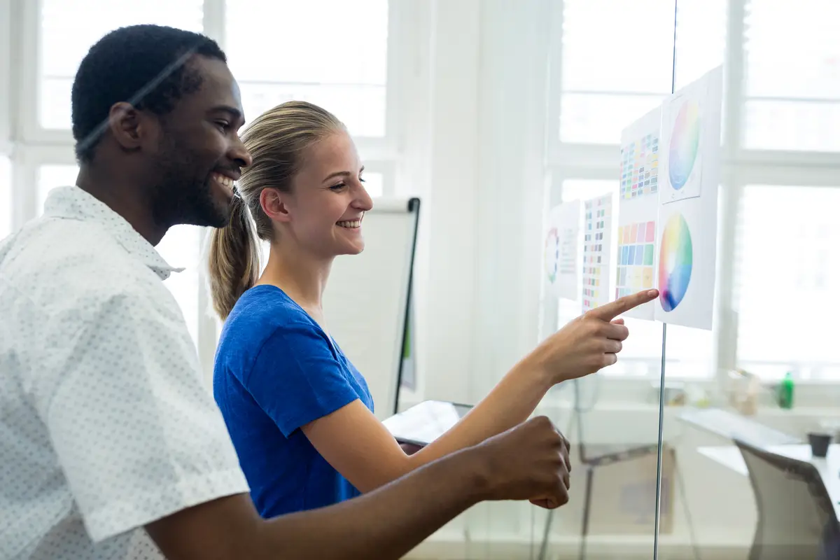 Male and female graphic designers interacting over color chart