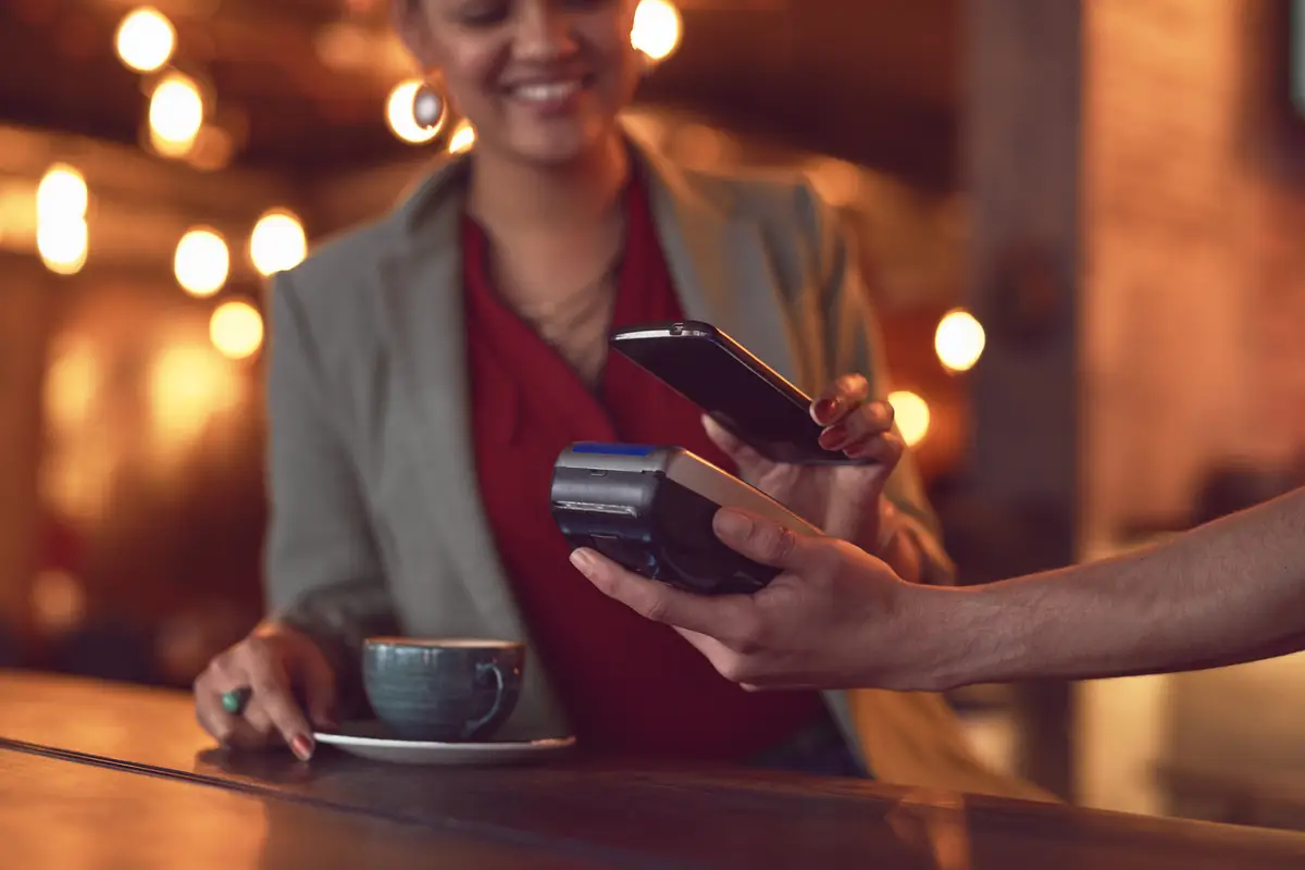 Coffee machine and woman paying with phone in cafe for online card payment with service Pos barista and female person with cellphone for electronic transaction for cappuccino in restaurant