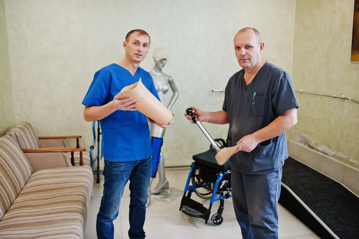 Two prosthetist man workers with prosthetic leg working in laboratory